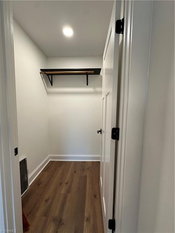 walk in closet with dark wood-style floors