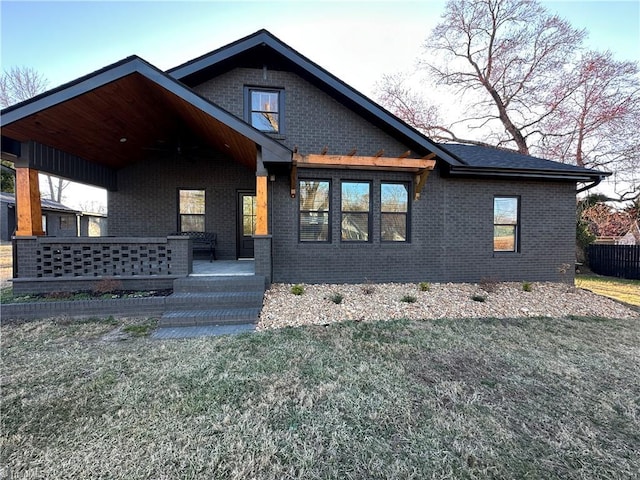 view of front facade with covered porch, a front yard, and brick siding