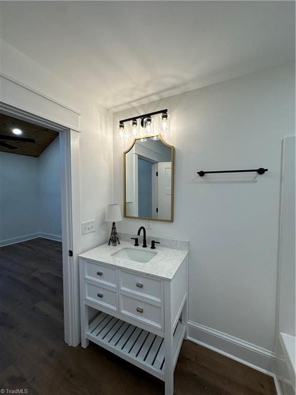 full bathroom with a tub, baseboards, wood finished floors, and vanity