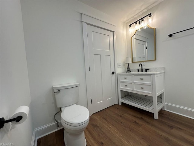 half bath featuring baseboards, wood finished floors, and vanity