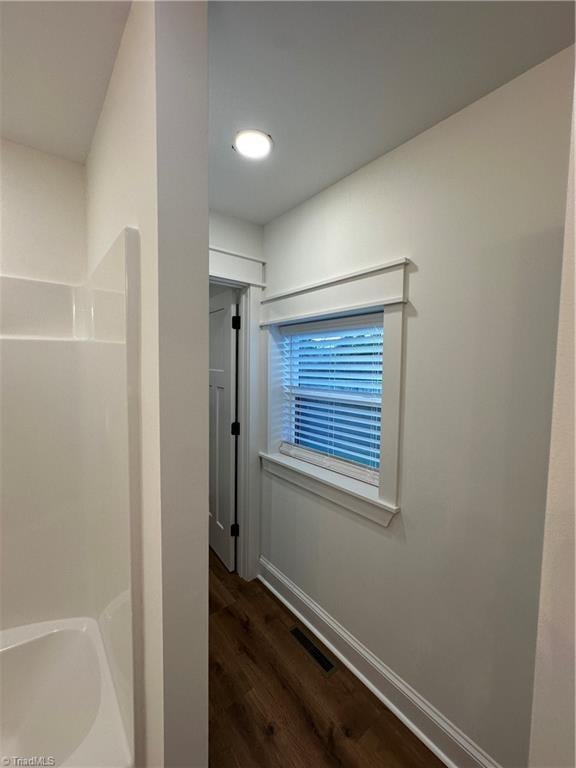 hallway with dark wood-style flooring, visible vents, and baseboards