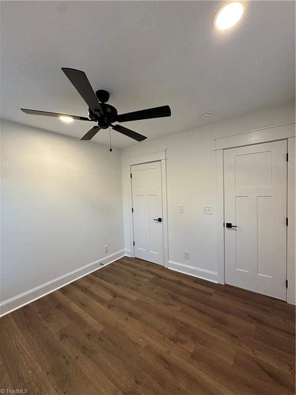 unfurnished bedroom featuring dark wood-style floors, baseboards, and a ceiling fan