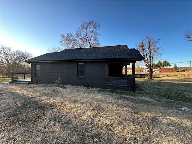 view of side of property with brick siding and roof with shingles