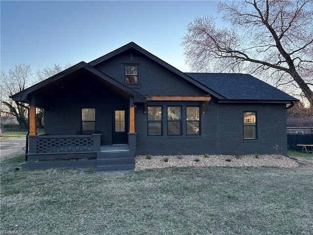 view of front facade featuring a front lawn, a porch, and brick siding