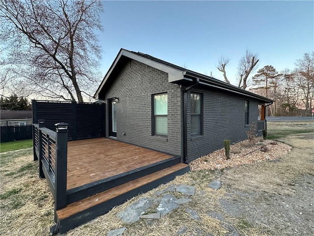 view of home's exterior with brick siding and a wooden deck