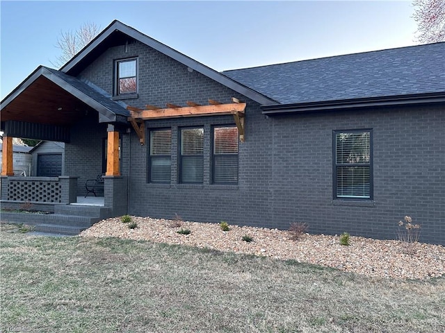 view of front of property featuring brick siding and roof with shingles