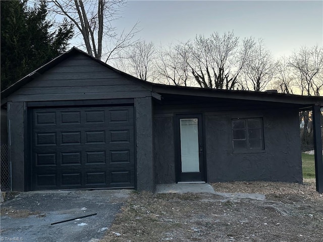 view of front of home with a garage, an outdoor structure, driveway, and stucco siding