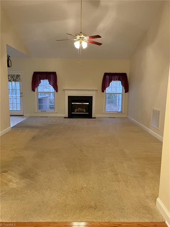 unfurnished living room featuring ceiling fan, plenty of natural light, light carpet, and lofted ceiling