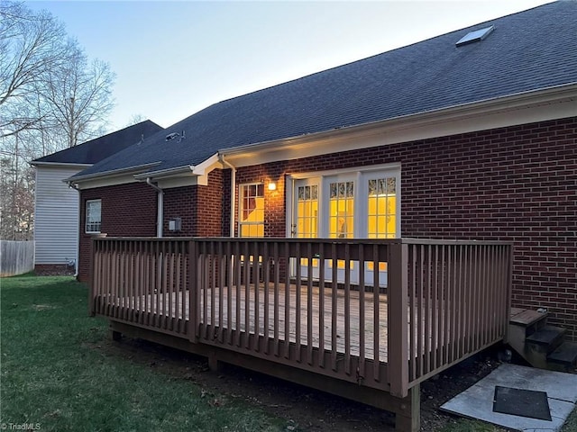 rear view of property featuring a lawn and a deck