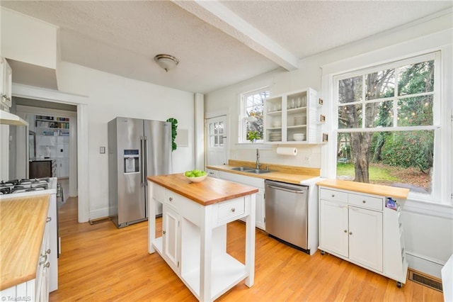 kitchen featuring a sink, appliances with stainless steel finishes, butcher block counters, and white cabinetry