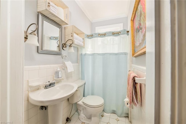 bathroom featuring toilet, ornamental molding, wainscoting, a shower with curtain, and tile walls