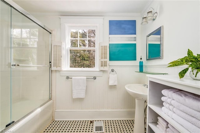 bathroom with crown molding, visible vents, shower / bath combination with glass door, and wainscoting