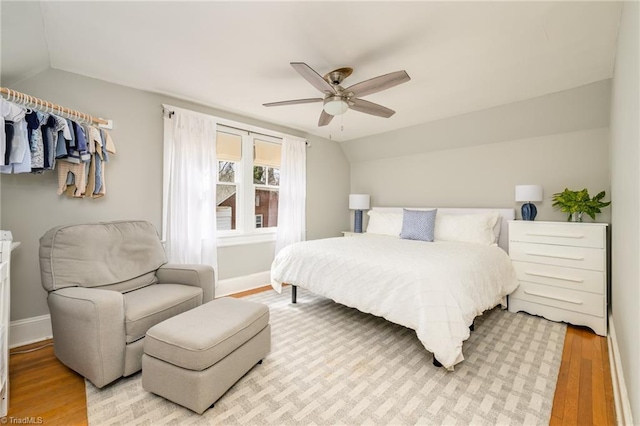 bedroom with baseboards, a ceiling fan, light wood-style floors, and vaulted ceiling