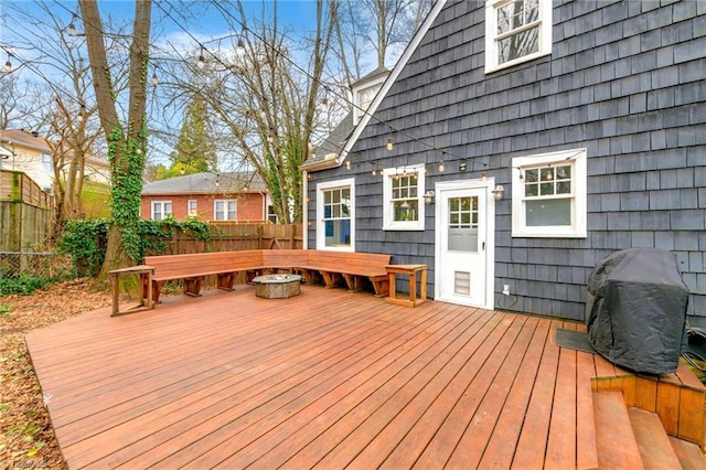 deck featuring an outdoor fire pit, a grill, and fence