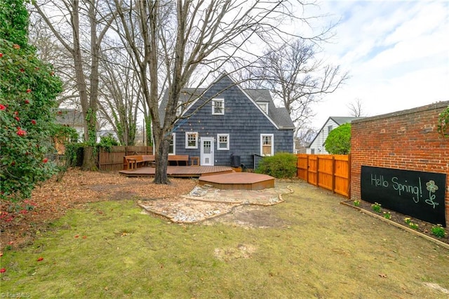 rear view of house with a yard, a deck, and fence