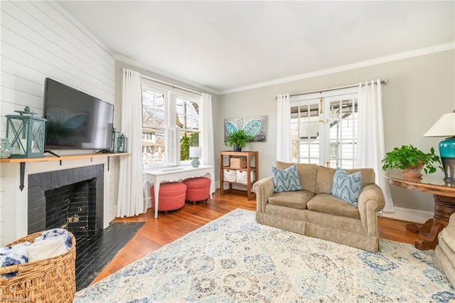 living area featuring a fireplace, wood finished floors, baseboards, and ornamental molding