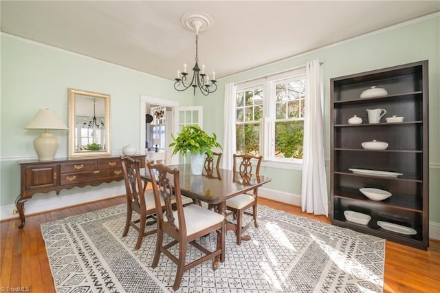 dining space featuring baseboards, an inviting chandelier, wood finished floors, and crown molding