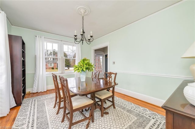 dining space with baseboards, a notable chandelier, and light wood finished floors