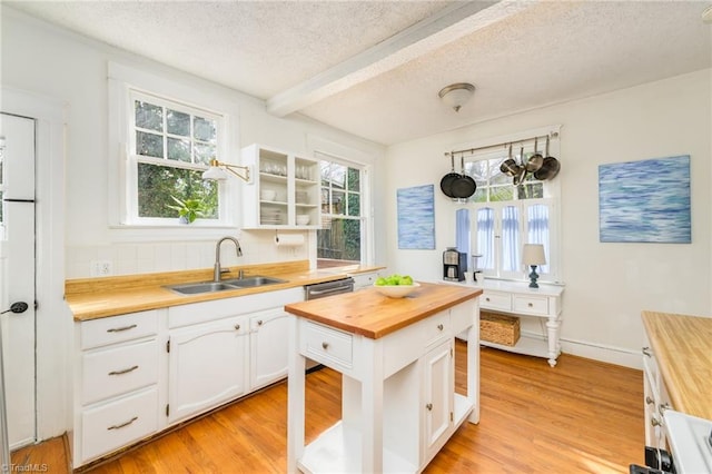 kitchen with a sink, white cabinets, light wood-type flooring, and butcher block counters