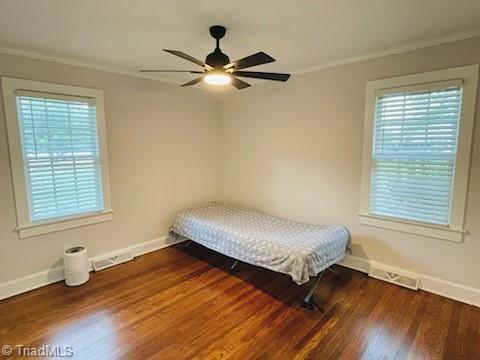 bedroom featuring ceiling fan, dark hardwood / wood-style flooring, and ornamental molding