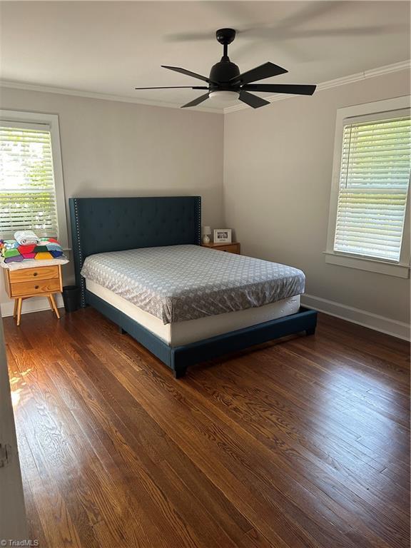 bedroom with ornamental molding, dark wood finished floors, baseboards, and a ceiling fan