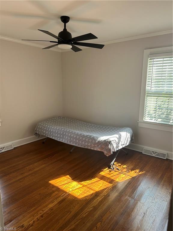 unfurnished bedroom with dark wood finished floors, visible vents, crown molding, and baseboards