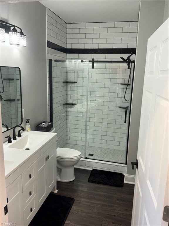 bathroom with toilet, walk in shower, wood-type flooring, and vanity