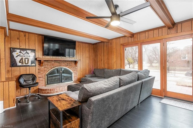 living room featuring beam ceiling, a fireplace, dark wood-type flooring, and wood walls