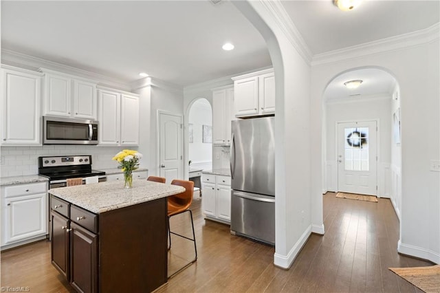 4 Harvest Oak Ct, Greensboro, NC 27406 - kitchen with appliances with stainless steel finishes, arched walkways, white cabinetry, ornamental molding, and decorative backsplash