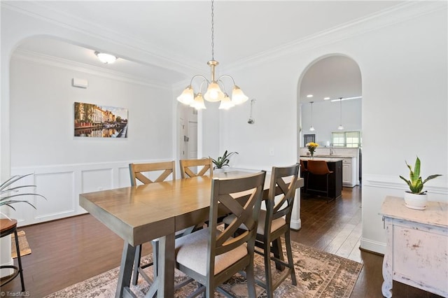 4 Harvest Oak Ct, Greensboro, NC 27406 - dining area featuring dark wood-type flooring, ornamental molding, arched walkways, a chandelier, and wainscoting