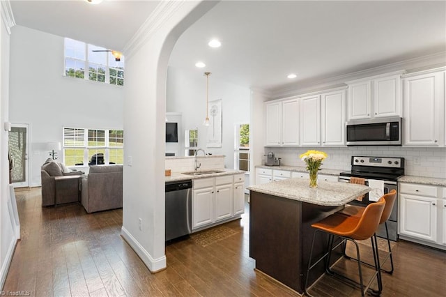 4 Harvest Oak Ct, Greensboro, NC 27406 - kitchen featuring stainless steel appliances, a sink, crown molding, arched walkways, and decorative backsplash