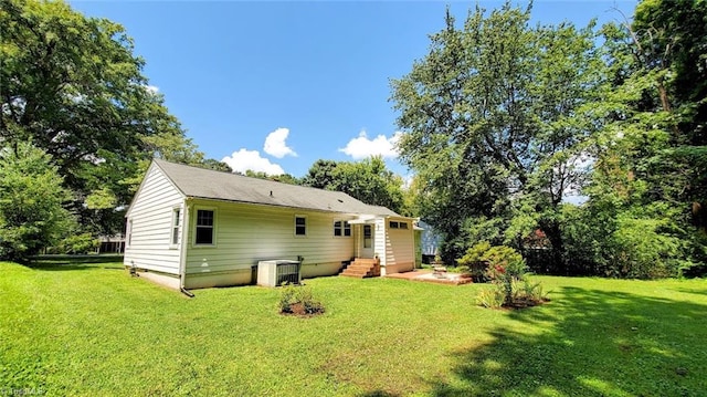 back of property featuring a lawn and central AC