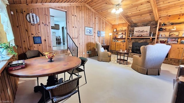 dining room with wood ceiling, built in shelves, vaulted ceiling, ceiling fan, and wood walls