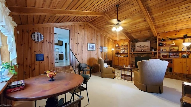 dining space featuring a fireplace, vaulted ceiling with beams, wooden walls, and wooden ceiling