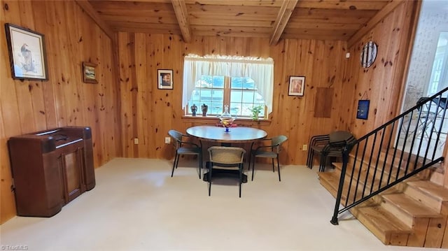 dining space featuring beam ceiling, wooden walls, carpet flooring, and wood ceiling