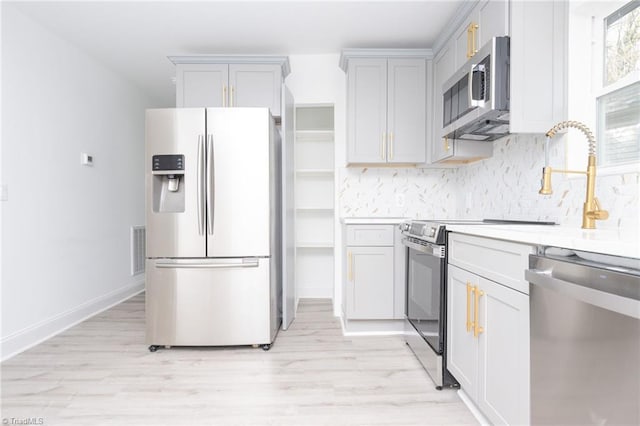 kitchen featuring stainless steel appliances, backsplash, and light wood-type flooring