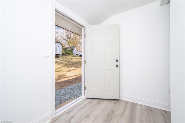 doorway with vaulted ceiling and light hardwood / wood-style floors