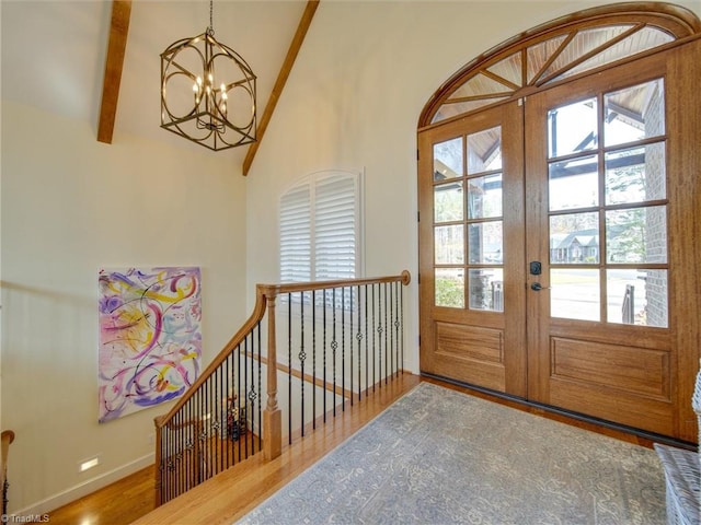 doorway to outside with a healthy amount of sunlight, wood-type flooring, beam ceiling, and french doors