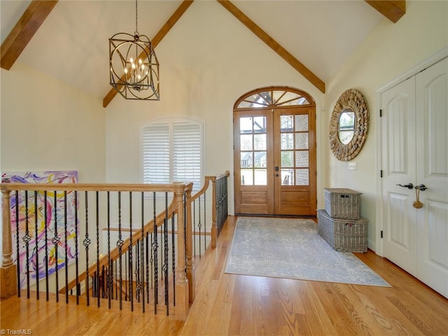 entrance foyer with beamed ceiling, light hardwood / wood-style flooring, high vaulted ceiling, and french doors