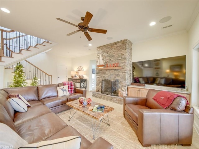 living room with a stone fireplace, ceiling fan, and crown molding