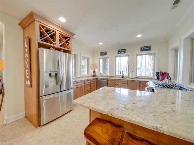 kitchen with kitchen peninsula, light brown cabinetry, a kitchen bar, stainless steel appliances, and crown molding