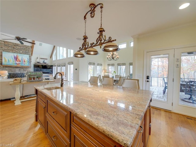 kitchen with a kitchen island with sink, sink, light stone countertops, and plenty of natural light