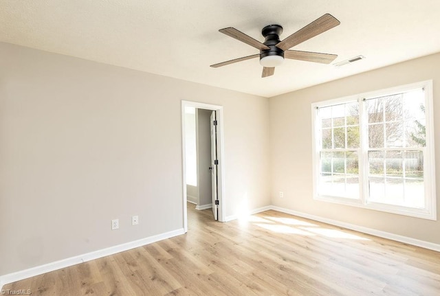 unfurnished room featuring light wood-style floors, baseboards, visible vents, and ceiling fan