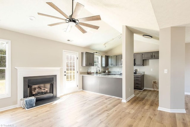 kitchen featuring a peninsula, light wood-type flooring, light countertops, and gray cabinetry