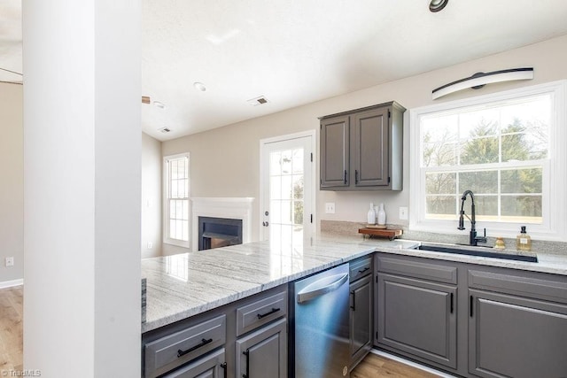 kitchen featuring visible vents, dishwasher, light stone countertops, gray cabinets, and a sink