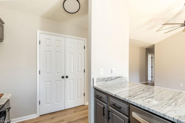 kitchen featuring gray cabinetry, a ceiling fan, baseboards, light wood-style floors, and light stone countertops