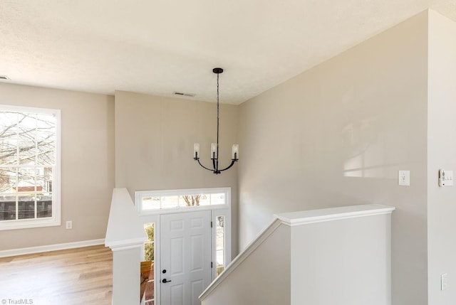 entryway with baseboards, light wood-style flooring, visible vents, and a notable chandelier