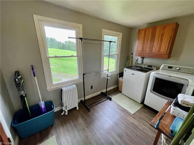 laundry room featuring washing machine and dryer, dark wood-type flooring, radiator heating unit, and cabinets