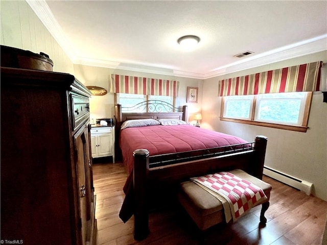 bedroom with ornamental molding, a baseboard heating unit, and wood-type flooring