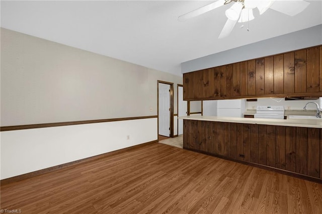 kitchen featuring sink, light hardwood / wood-style flooring, kitchen peninsula, stove, and white fridge